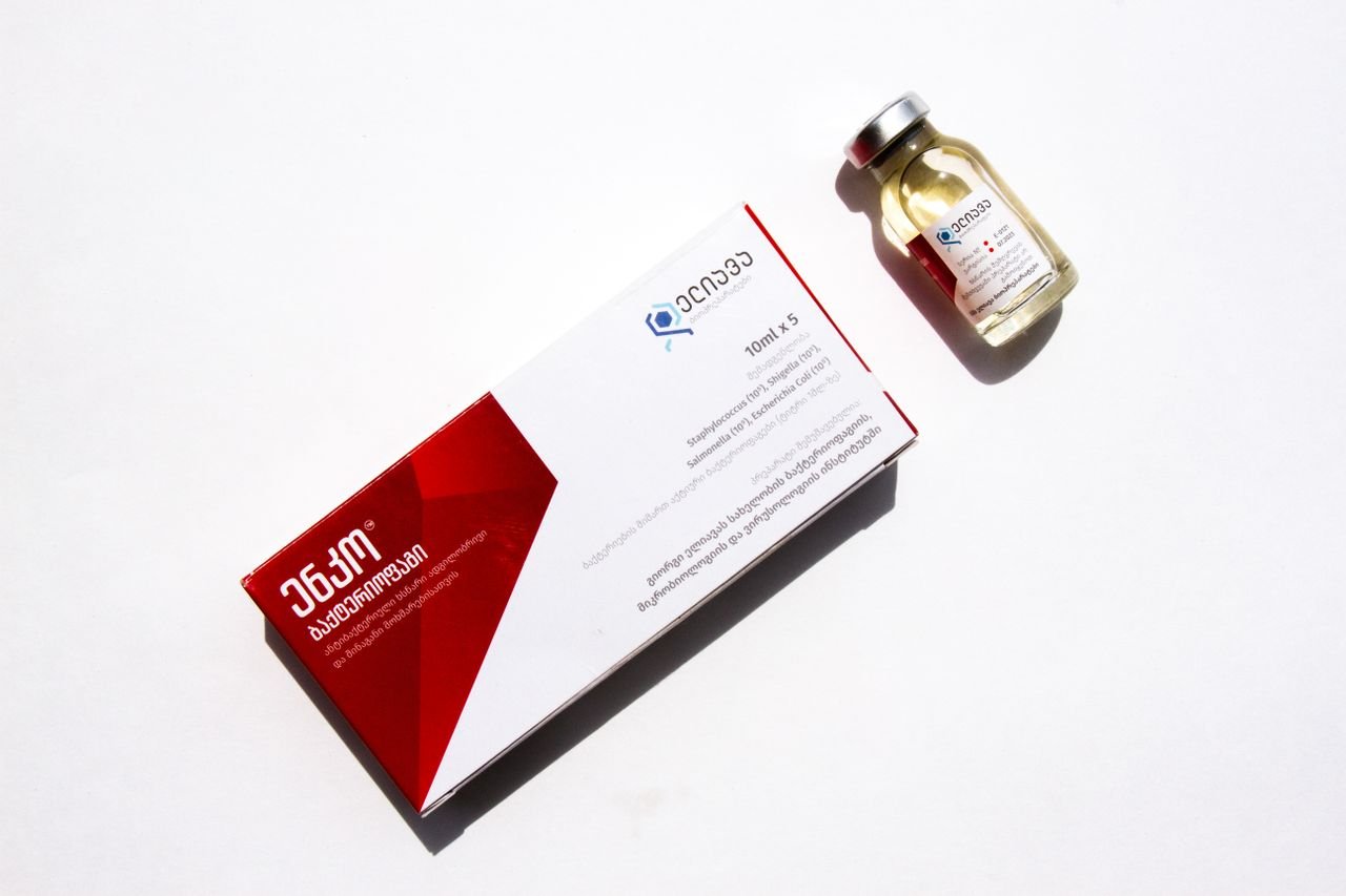 who-we-are High-angle view of medicine box and vial on a white background with Georgian text.